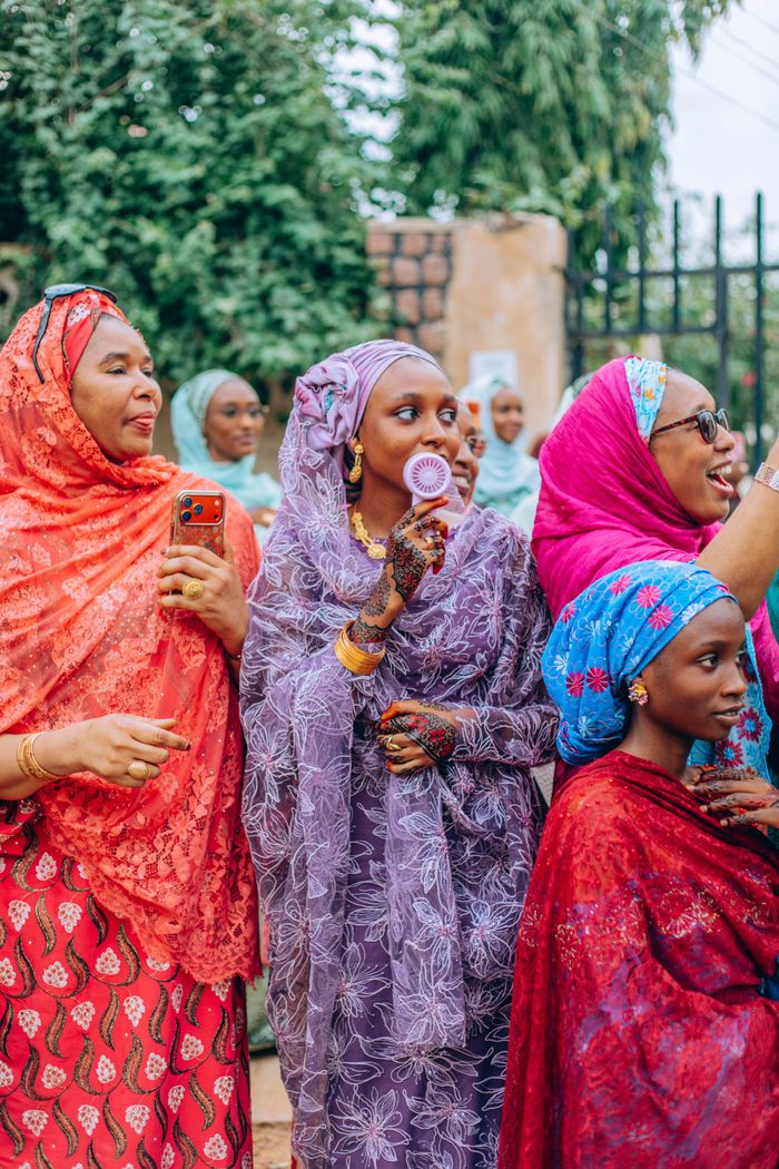 Group of women in vibrant traditional African attire enjoying an outdoor gathering.